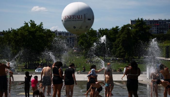 Pessoas brincam em uma fonte no Parque André Citroën enquanto as temperaturas sobem em Paris, d...