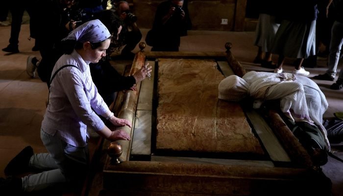 Devotos beijam a Pedra da Unção, dentro da Basílica do Santo Sepulcro, em Jerusalém. (Foto: A...